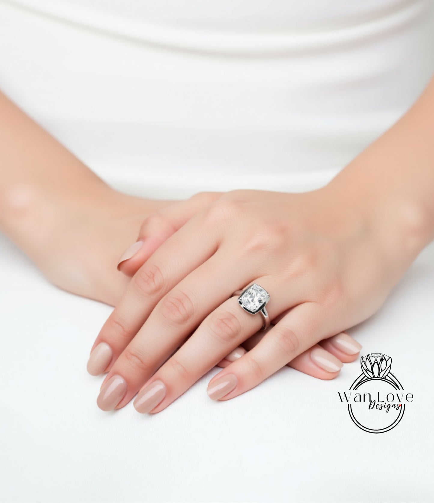A close-up of a person's hands resting on a white surface, with a large diamond ring visible on one of the fingers.