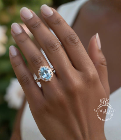 A close-up of a person's hand wearing a gold ring with a large blue gemstone, likely an aquamarine or blue topaz stone.