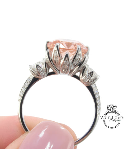 A close-up image of a person's hand holding a silver ring with a large, pink gemstone.