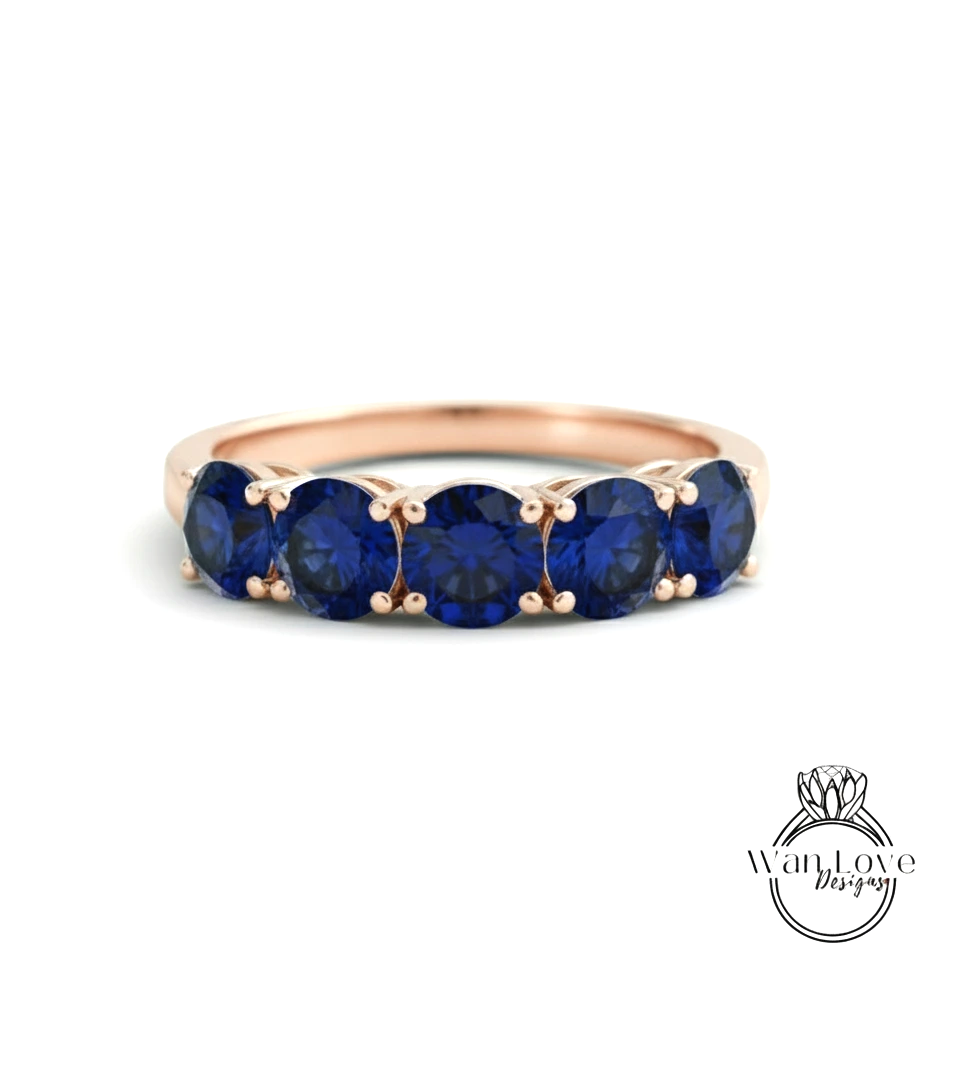 A gold ring with a row of blue sapphire gemstones set in the band.