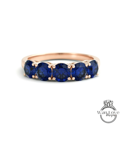 A gold ring with a row of blue sapphire gemstones set in the band.