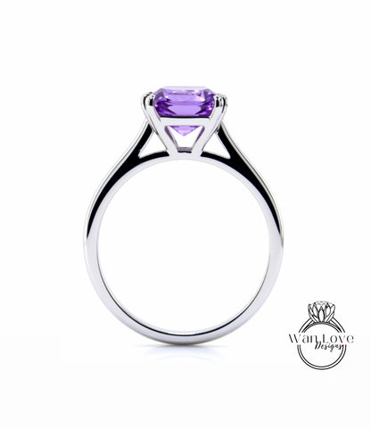 A silver engagement ring with a large, clear purple gemstone set in the center.