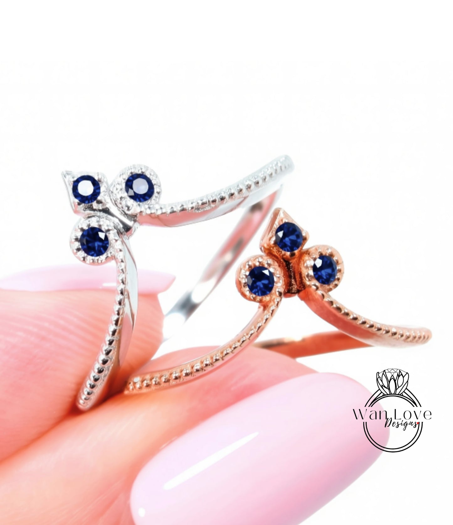 A close-up image of a person's hand holding two rings with blue gemstones.