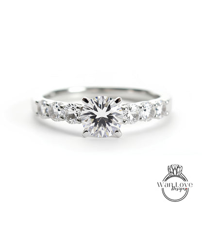 A close-up view of a diamond engagement ring with a large central diamond surrounded by smaller diamonds on either side.