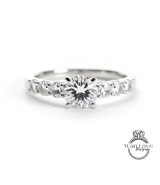 A close-up view of a diamond engagement ring with a large central diamond surrounded by smaller diamonds on either side.