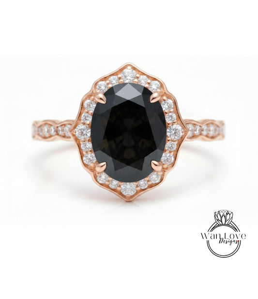 A rose gold ring with a large oval-shaped black gemstone set in a scalloped bezel, surrounded by smaller diamonds.