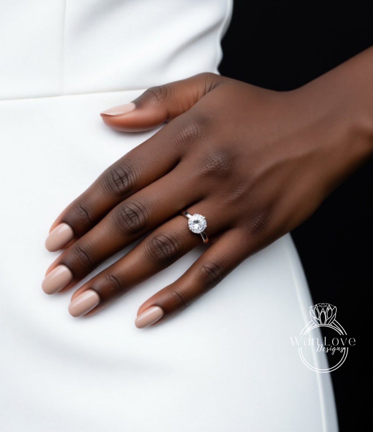 A close-up of a hand wearing a diamond engagement ring, with a white dress visible in the background.