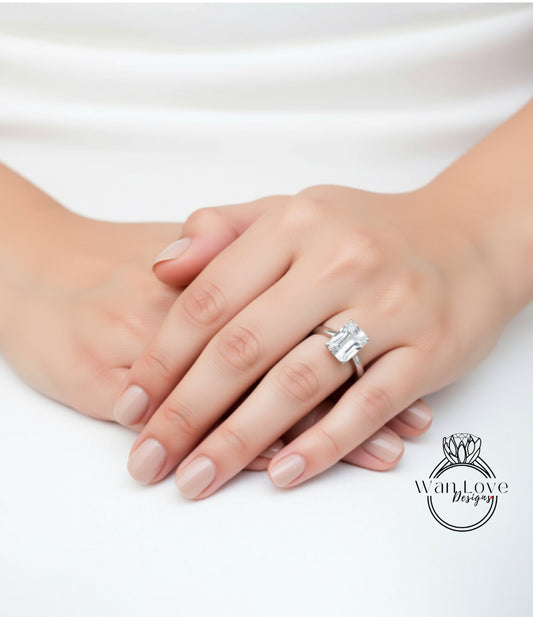 A close-up of a person's hands with a large diamond engagement ring on the ring finger.