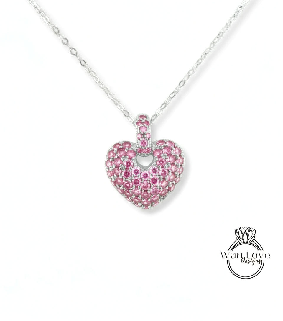 A heart-shaped pendant necklace with a large, sparkling pink gemstone in the center.