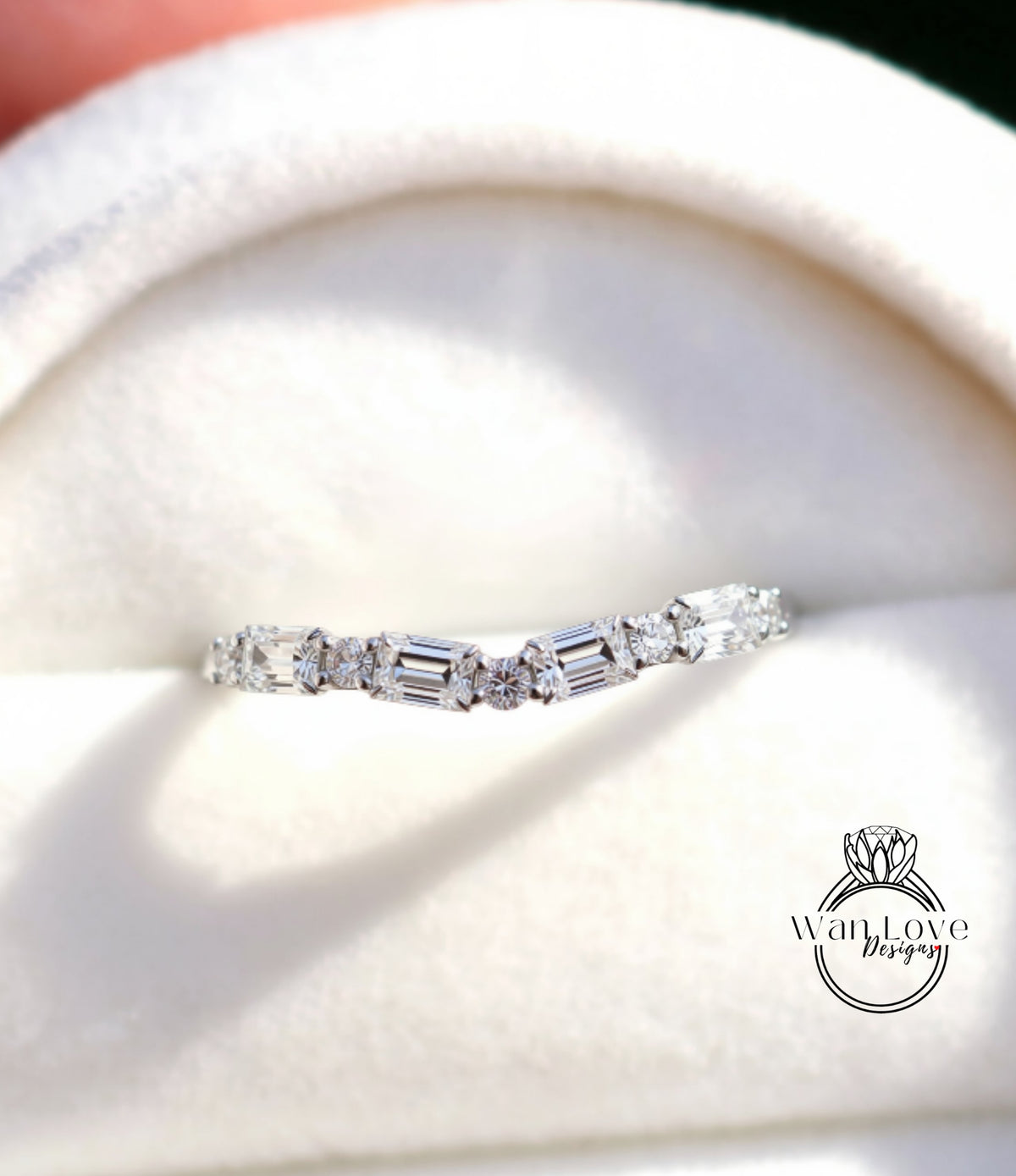 A close-up view of a diamond engagement ring displayed on a white fabric background.