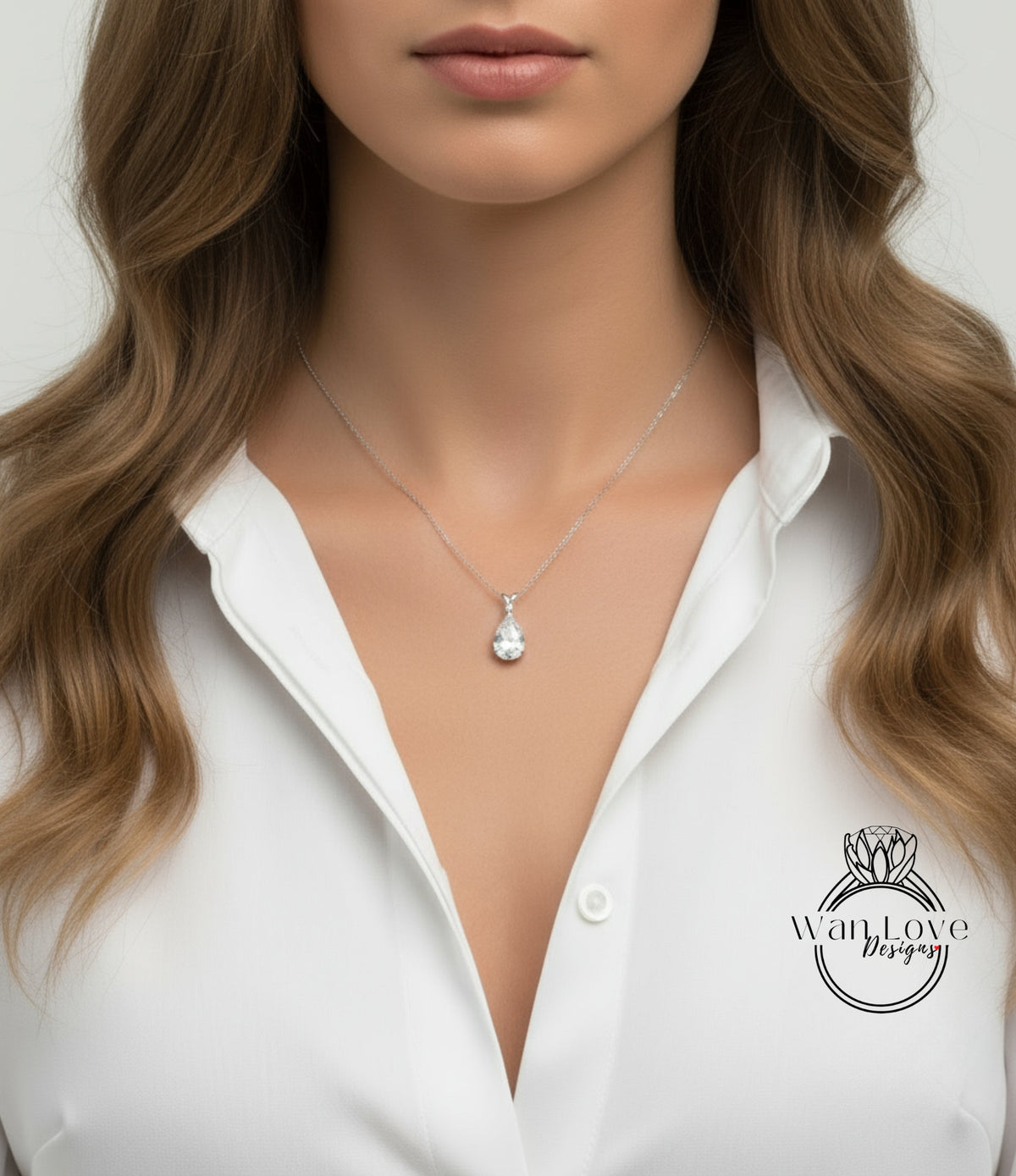 A close-up of a woman's neck and chest wearing a white blouse with a delicate necklace featuring a pendant.