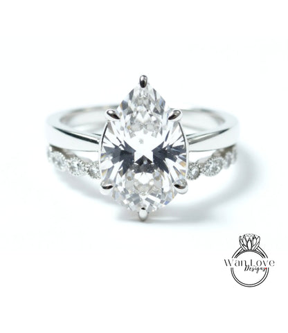 A close-up of a diamond engagement ring with a large pear-shaped diamond set in a silver band.