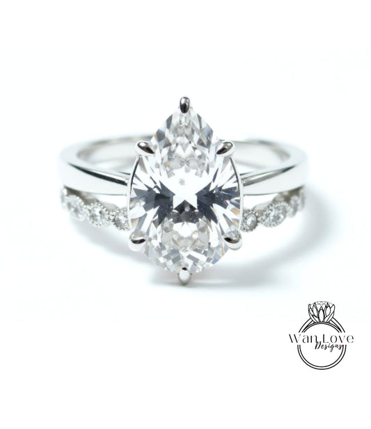 A close-up of a diamond engagement ring with a large pear-shaped diamond set in a silver band.