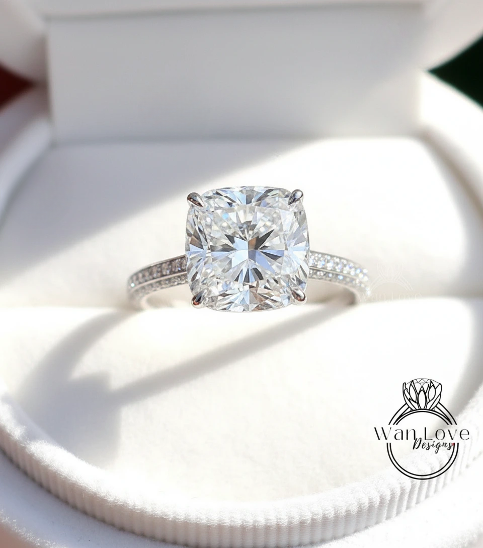 A large, brilliant-cut diamond engagement ring is displayed in a white box, showcasing its sparkling clarity and elegant design.