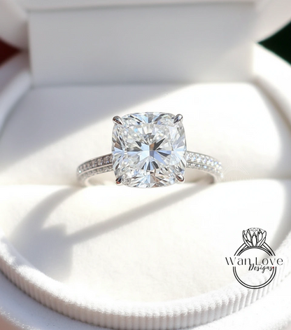 A large, brilliant-cut diamond engagement ring is displayed in a white box, showcasing its sparkling clarity and elegant design.