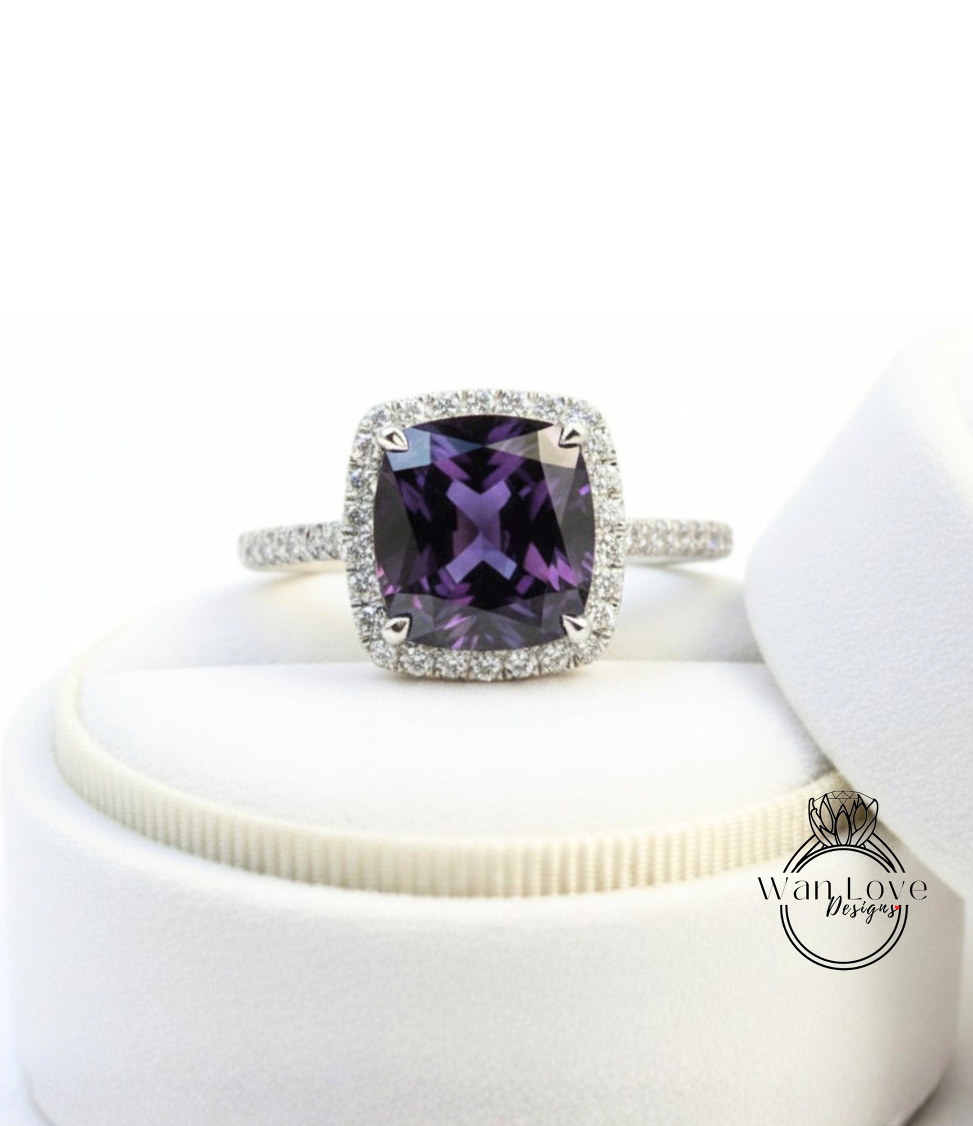 A ring with a large purple gemstone set in a halo of smaller diamonds, displayed on a white surface.