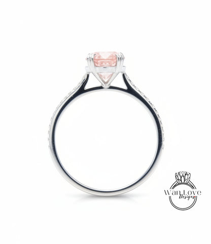 A silver ring with a large pink gemstone, possibly a diamond, set in the center.