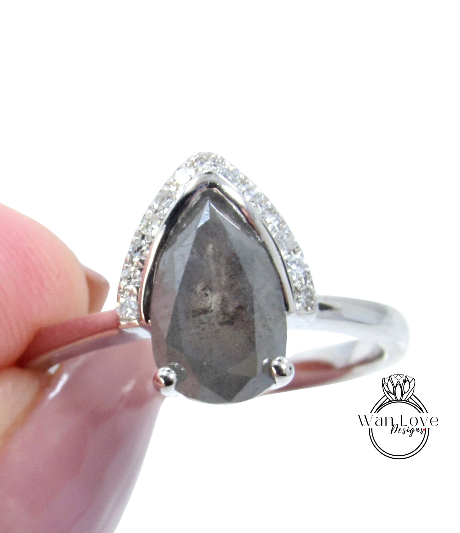 A close-up image of a silver ring with a large, irregularly shaped gray diamond as the centerpiece, surrounded by smaller diamonds.