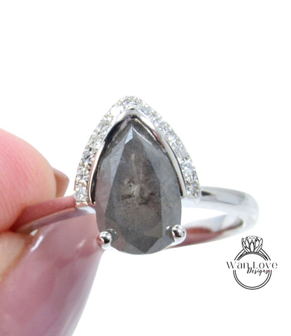 A close-up image of a silver ring with a large, irregularly shaped gray diamond as the centerpiece, surrounded by smaller diamonds.