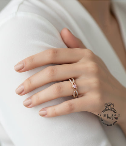 A close-up of a hand wearing a gold ring with a pink gemstone.
