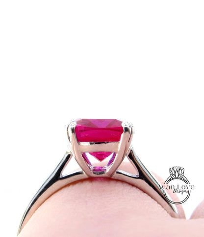 A close-up view of a silver ring with a large, vibrant pink gemstone set in the center.