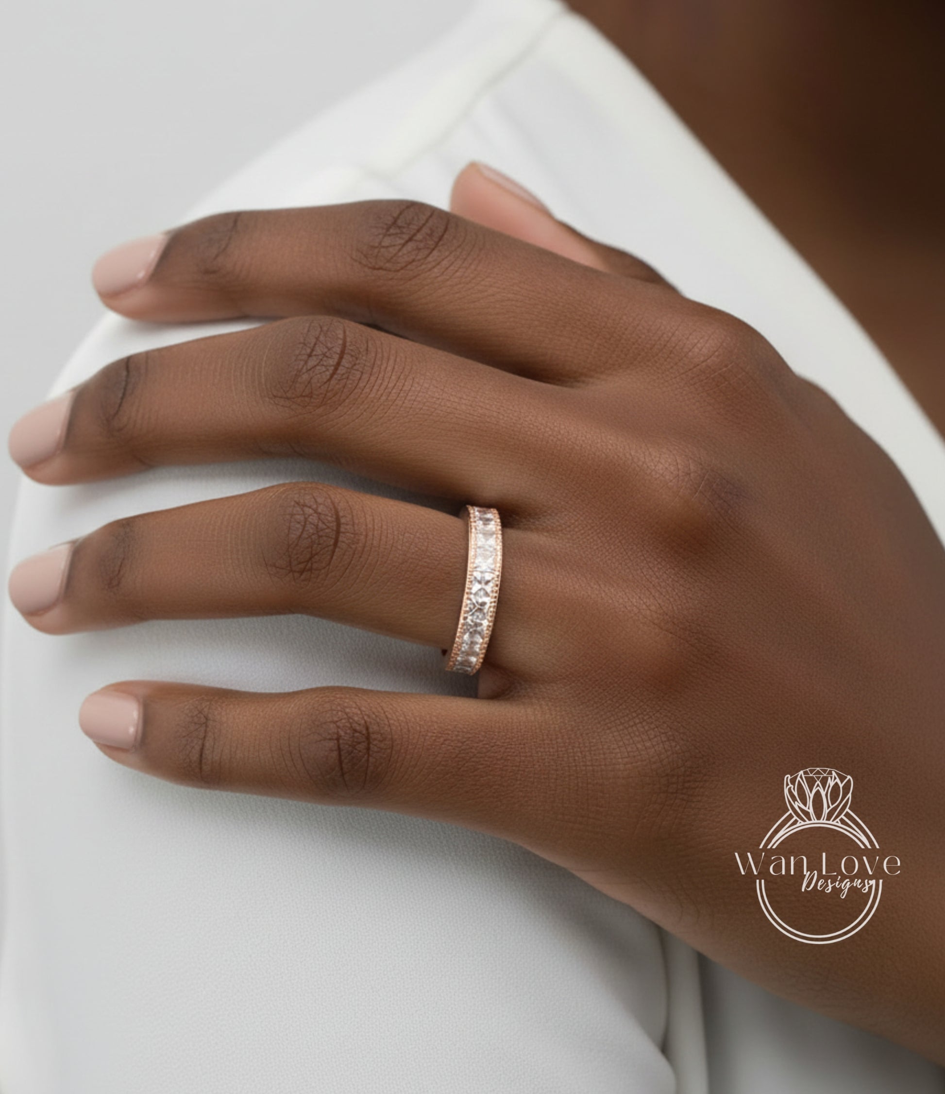 A close-up of a person's hand wearing a gold ring with a row of small diamonds.