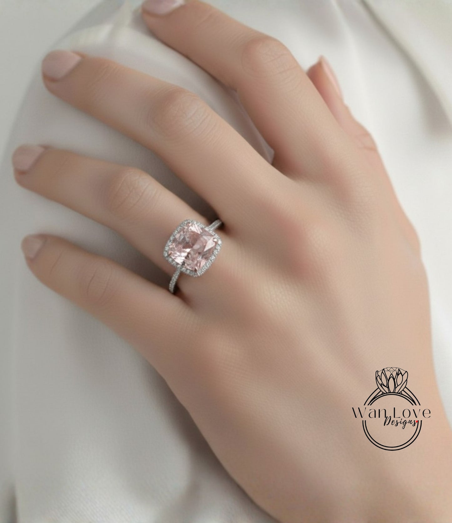 A close-up of a hand wearing a large, pink gemstone ring with a halo around it.