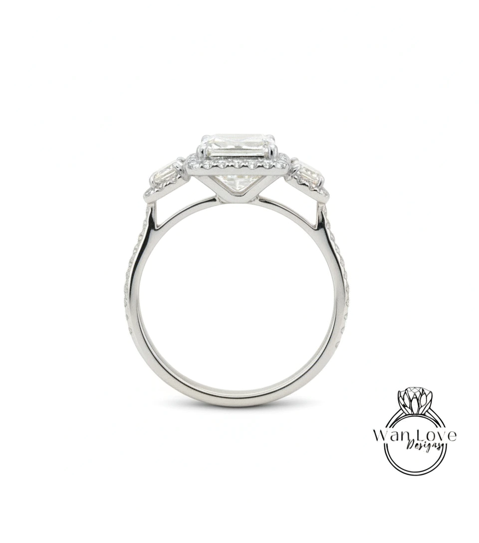 A silver engagement ring with a large central diamond surrounded by smaller diamonds on either side.
