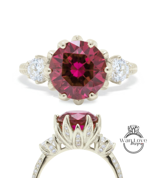a beautiful engagement ring with a large, deep red gemstone set in a silver band. The ring is adorned with smaller diamonds that add to its elegance and sparkle.