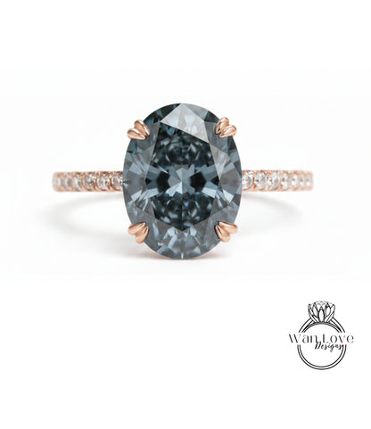 A close-up of a large, dark blue diamond ring with a rose gold band and small diamonds around the band.
