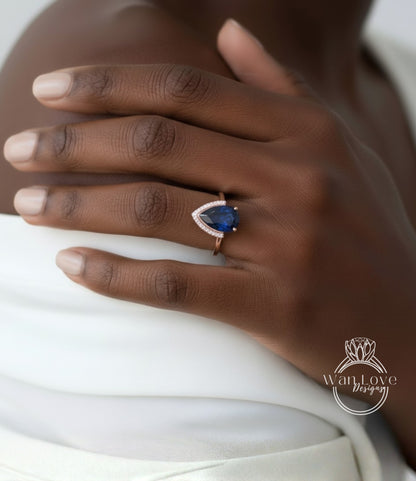 A close-up of a person's hand wearing a ring with a blue gemstone.