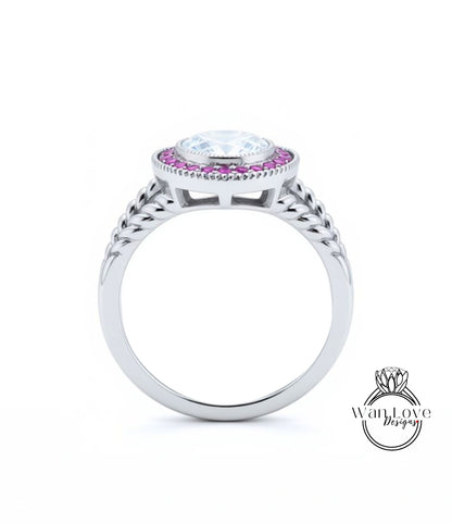 A silver ring with a large central gemstone surrounded by smaller stones, and a decorative band with braided patterns.