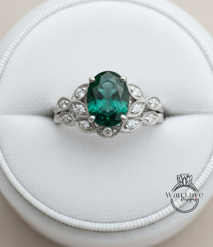 A silver ring with a large oval-shaped green gemstone, surrounded by smaller diamonds, placed in a white jewelry box.
