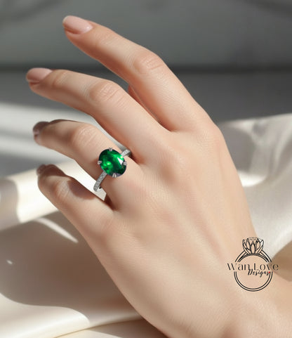A close-up of a hand wearing a ring with a large, oval-shaped green gemstone.