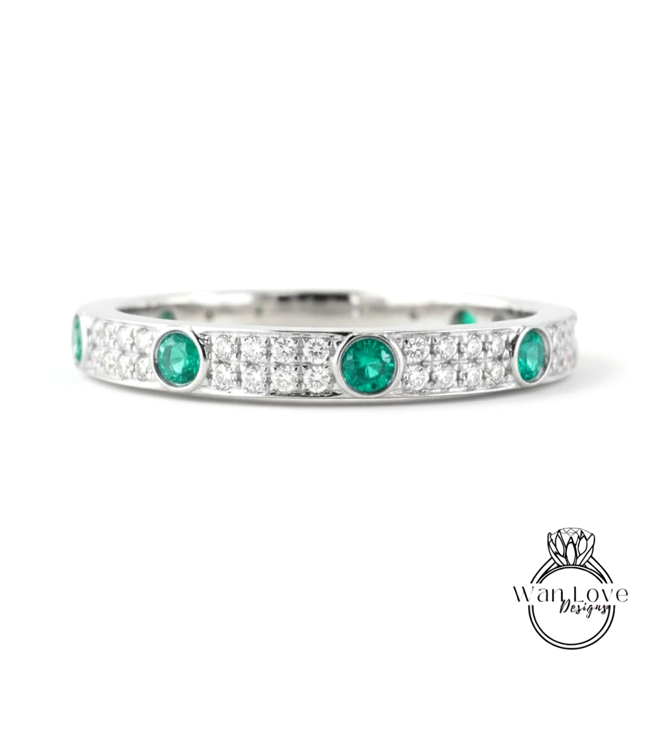 A silver band with a row of green gemstones and diamonds set in it.