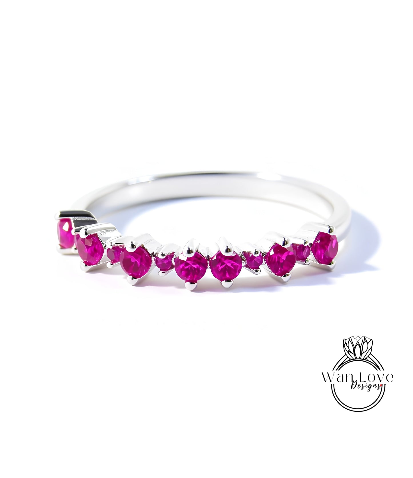 A silver ring with a row of pink gemstones, likely rubies, set in a band.