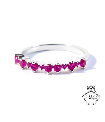 A silver ring with a row of pink gemstones, likely rubies, set in a band.
