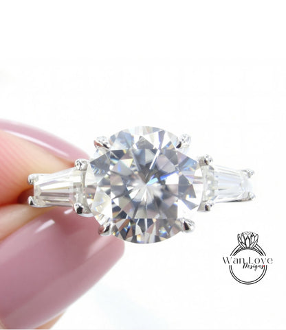 A close-up image of a person's hand holding a diamond engagement ring with a large, brilliant-cut diamond set in a silver band.