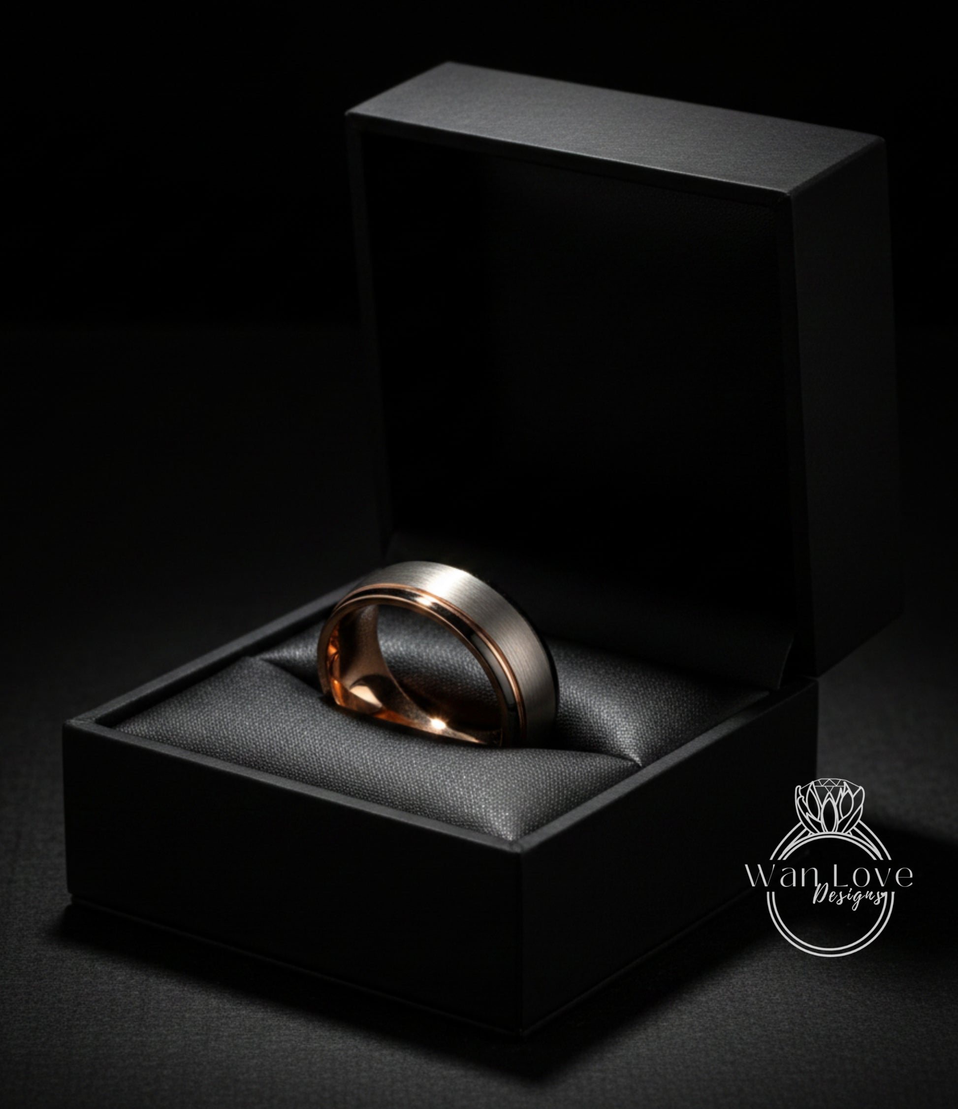 A gold-toned ring is displayed in an open black jewelry box against a dark background.