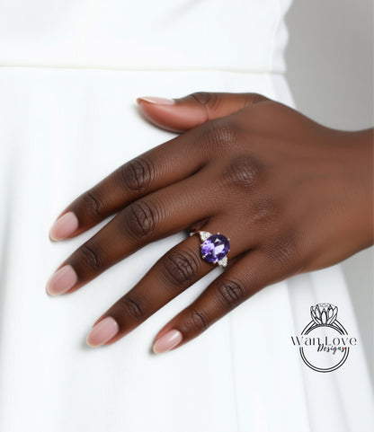 A close-up of a hand wearing a ring with a large purple gemstone.