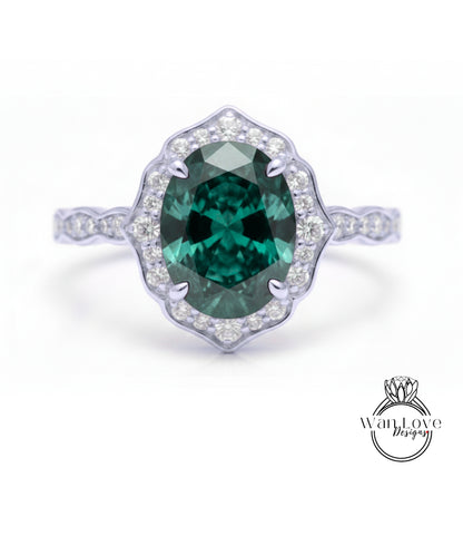 A stunning engagement ring with a large oval-shaped green gemstone set in a halo of smaller diamonds, surrounded by a scalloped edge.