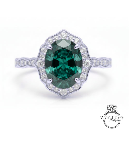 A stunning engagement ring with a large oval-shaped green gemstone set in a halo of smaller diamonds, surrounded by a scalloped edge.