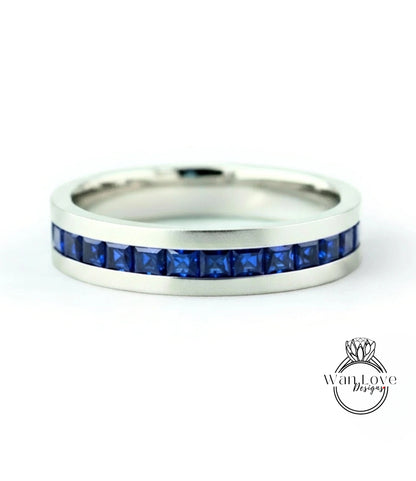 A silver band ring with a row of blue gemstones, specifically sapphires, set in the band.