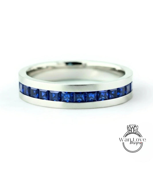 A silver band ring with a row of blue gemstones, specifically sapphires, set in the band.