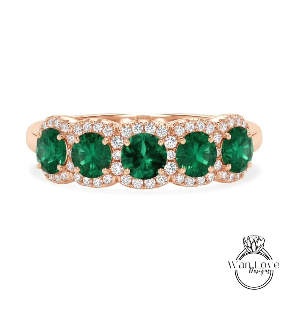 A rose gold ring with a row of green gemstones, including diamonds, set in the center.