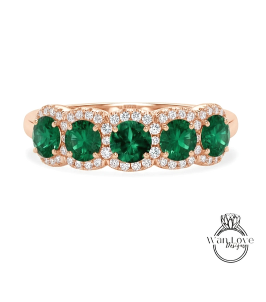 A rose gold ring with a row of green gemstones, including diamonds, set in the center.