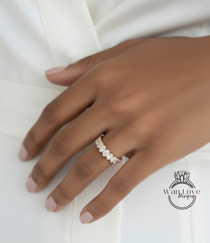 A close-up of a hand wearing a gold ring with a row of small diamonds on the band.