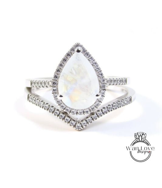 A silver ring with a large pear-shaped gemstone, surrounded by smaller diamonds, and a halo of smaller diamonds around the top of the gemstone.