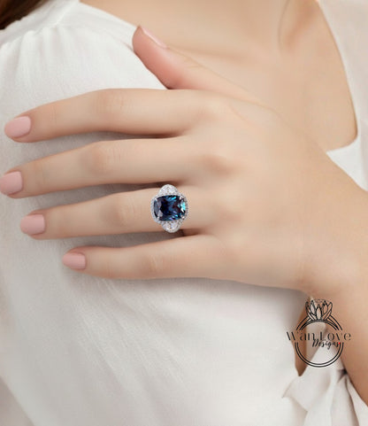 A close-up of a person's hand wearing a large, blue gemstone ring on the ring finger.