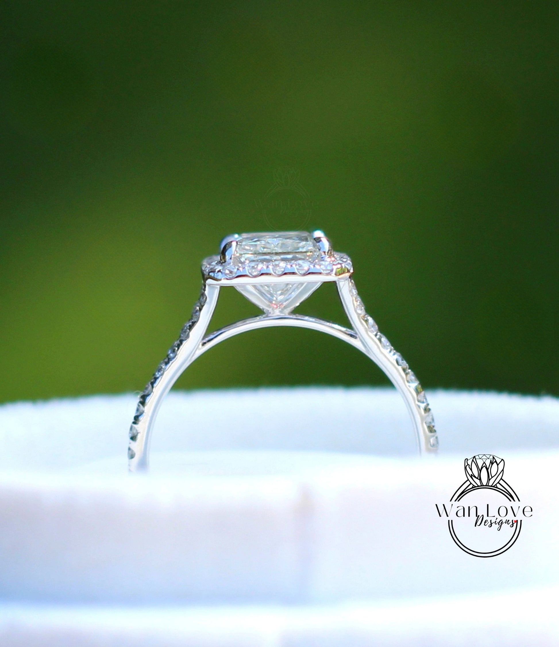 A close-up view of a diamond engagement ring with a large central diamond surrounded by smaller diamonds, set in a halo of smaller diamonds.